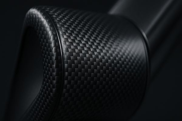 A close-up of a carbon fiber component, showing the woven texture and its sleek, high-tech appearance