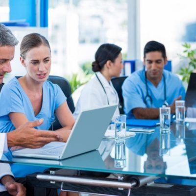 Medical team in meeting room using laptop for clinical case discussion