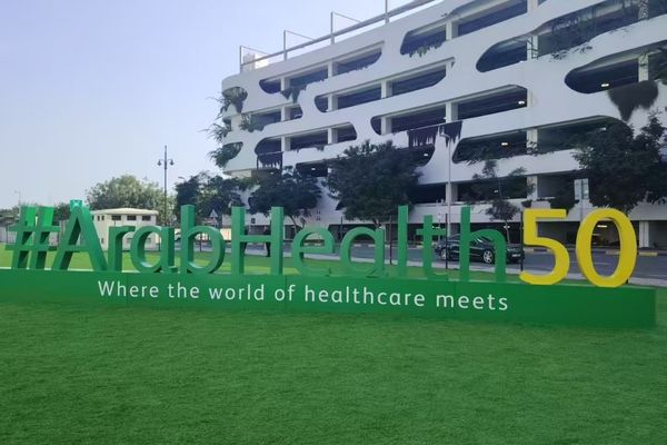 Arab Health 50th anniversary sign with green lawn and modern building in the background