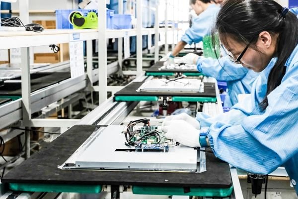 Reshin factory assembly line with technician assembling circuit boards and modules of medical displays to ensure performance and reliability.