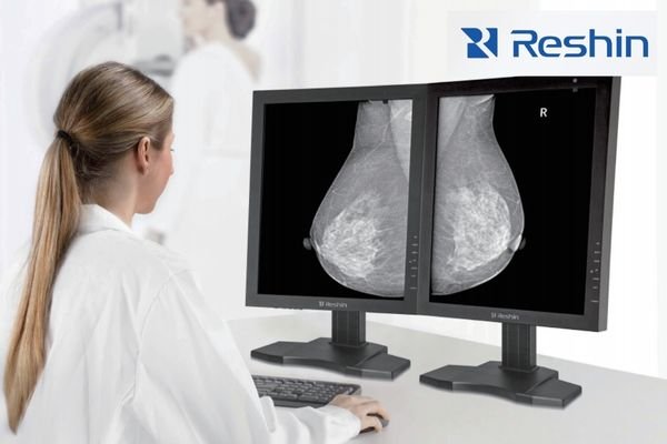 Radiologist reviewing mammograms on dual medical-grade displays with DICOM calibration.