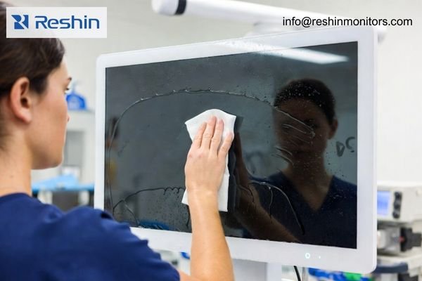 An image showing a medical professional cleaning an optical-bonded OEM medical monitor by Reshin in a clinical setting, demonstrating its seamless surface and fluid resistance