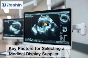 Medical-grade monitor on a clinical mount showing non-identifiable imaging, with supplier evaluation materials like a checklist, PCN notice, SLA card, and calibration puck.