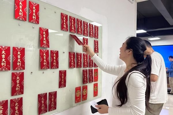 Reshin employees taking part in a Lantern Festival activity and drawing red envelopes from an interactive wall display.