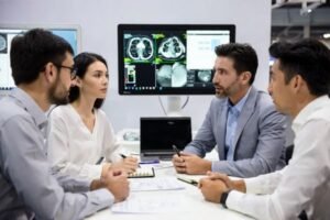 Profesionales analizando los requisitos de un proyecto OEM de monitores médicos en una mesa de reunión dentro de un stand de feria