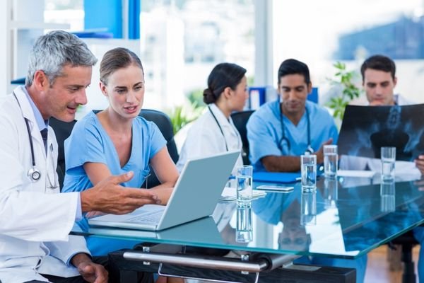 Médicos y personal sanitario revisando juntos resultados de imagen médica durante una reunión de equipo en el hospital